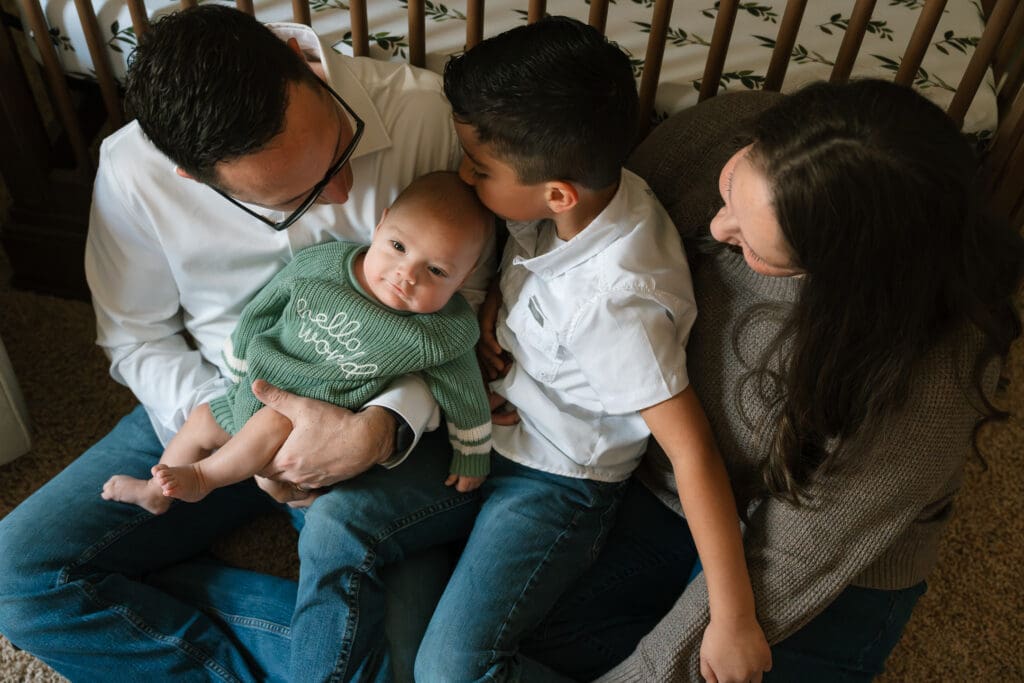 Family sitting together on a couch with their baby during a relaxed in-home lifestyle family photo session.