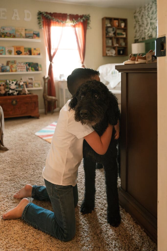 little boy hugging family pet in room during lifestyle session in chattanooga, tn
