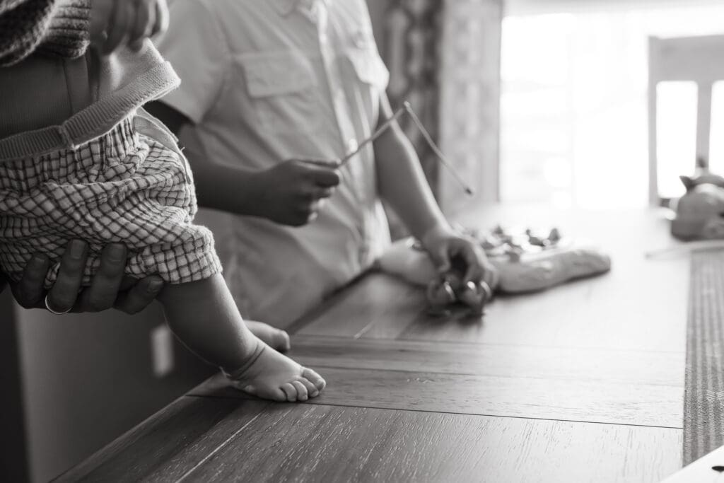 close up of baby's feet and older sibling playing a game during documentary photography session