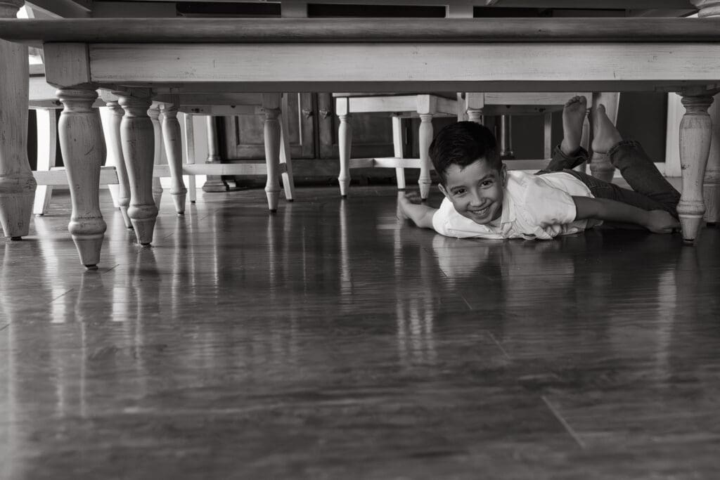 little boy smiling under the dining room table during documentary photography session
