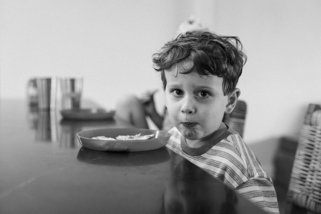 little boy eating snack at kitchen table