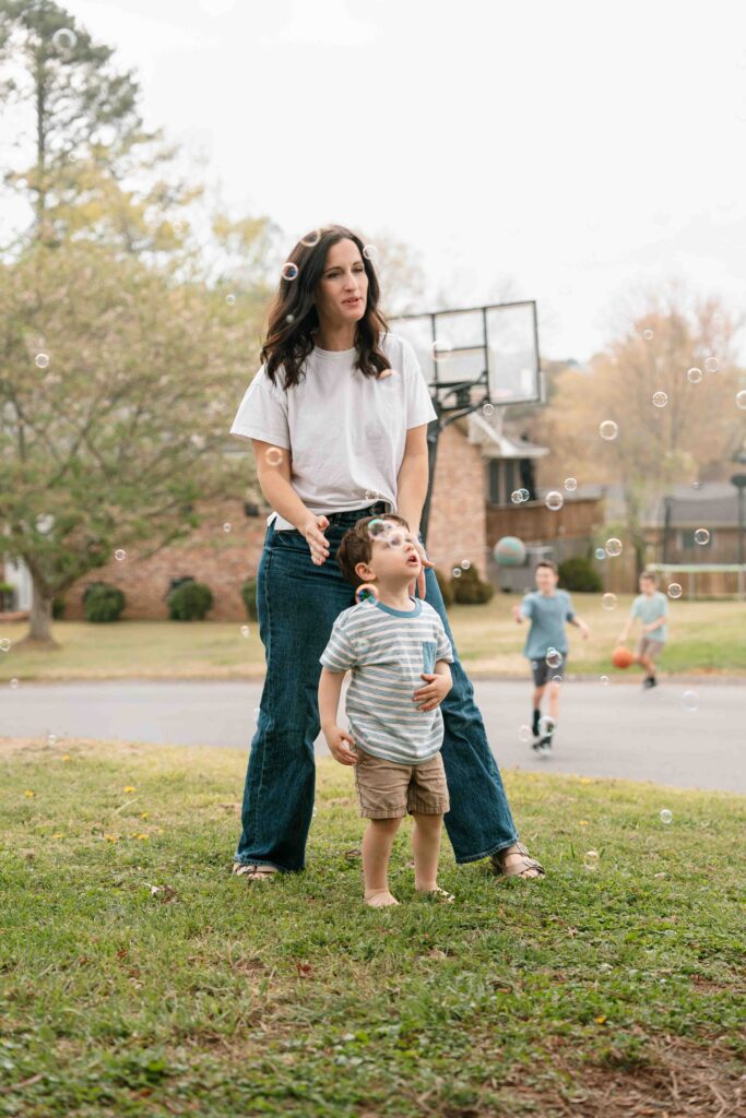 mom and little boy playing in bubbles outside of home