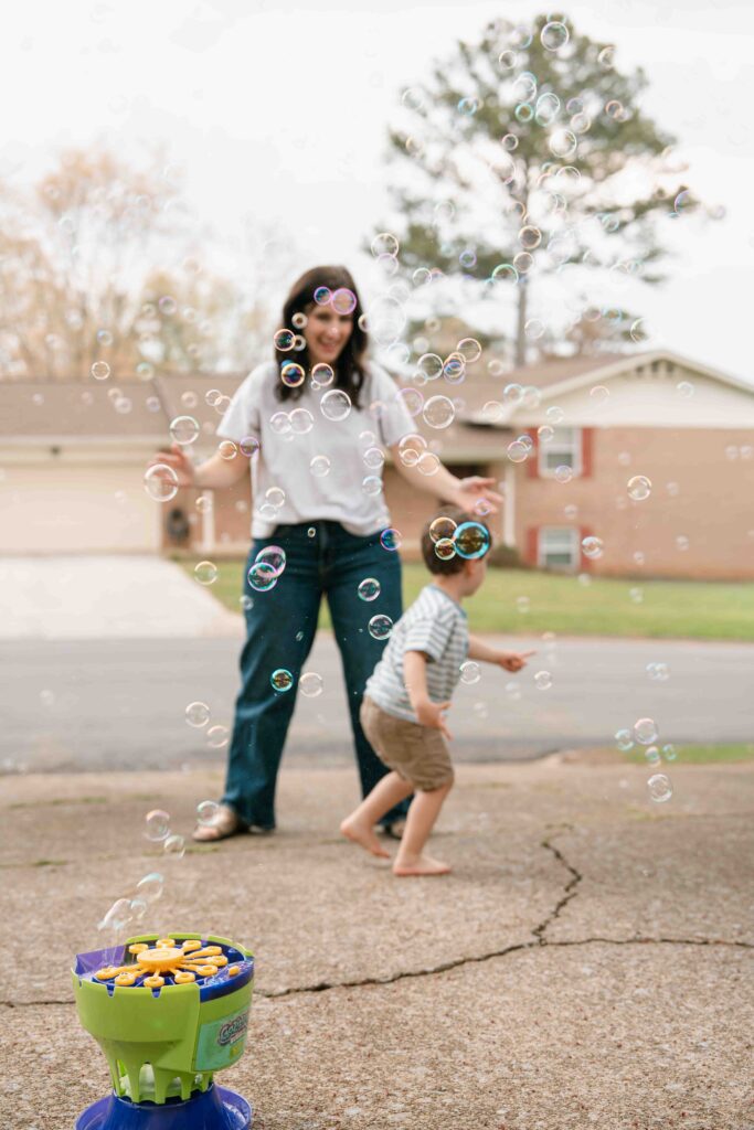 mom and little boy playing with bubbles outside