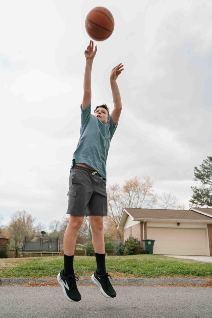 teenage boy shooting basketball in driveway