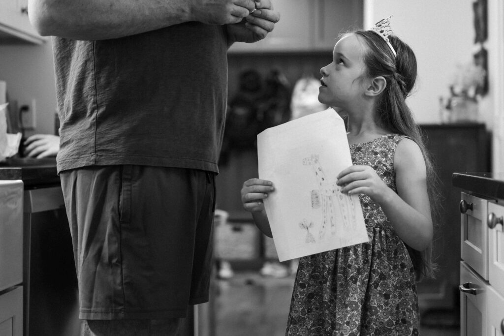 little girl showing dad her drawing she made