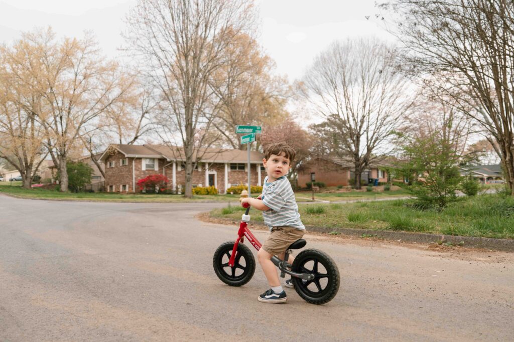 little boy riding bike down the street of home