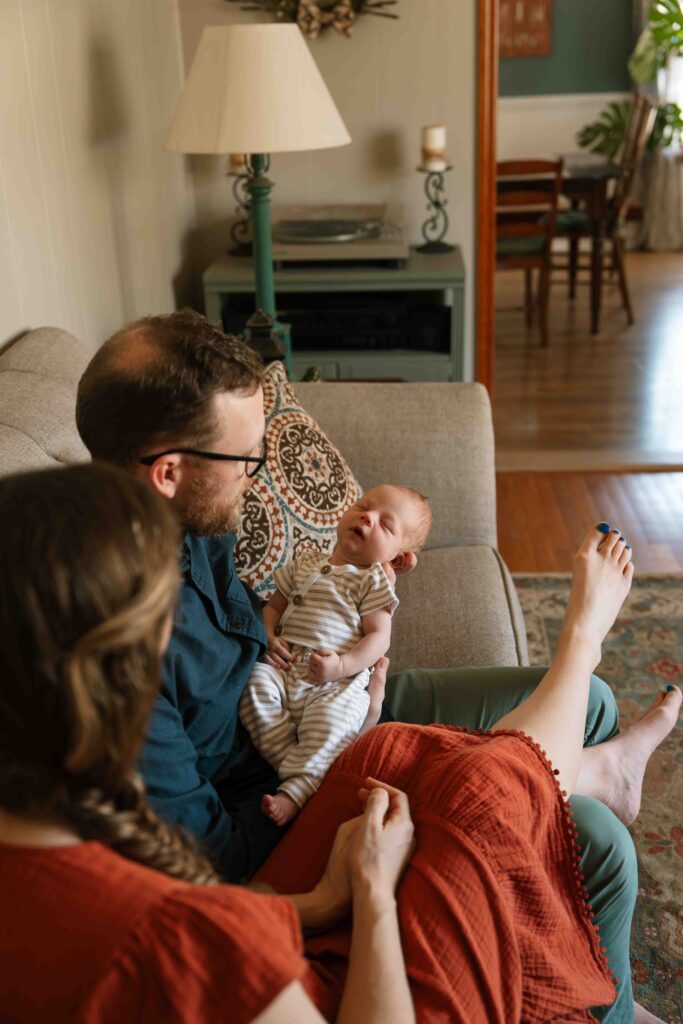 mom and dad holding baby on couch