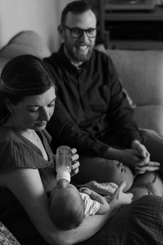 mom and dad feeding baby on couch