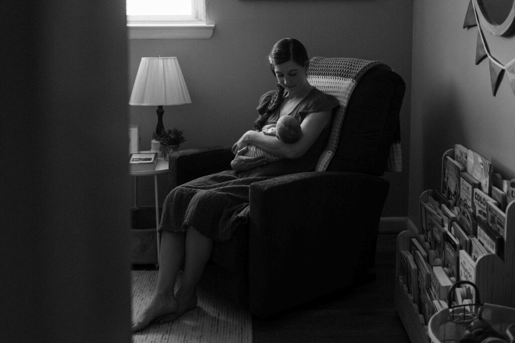mom holding newborn in nursery chair