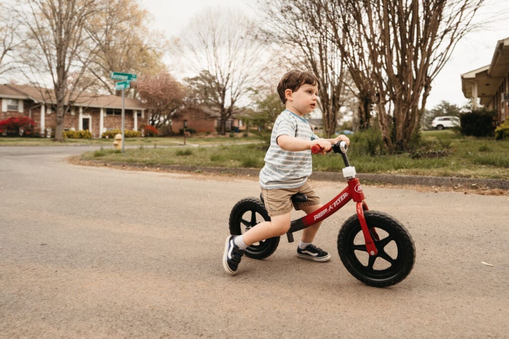 little boy riding bike down the street of home