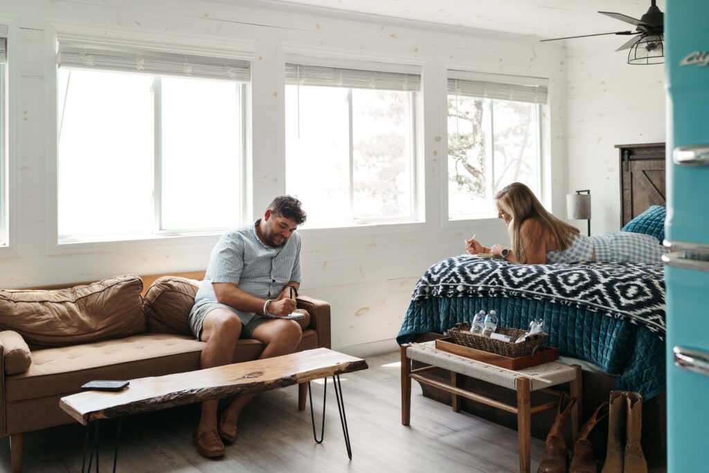 Couple writing letters to each other in a sunlit cabin before their elopement ceremony.